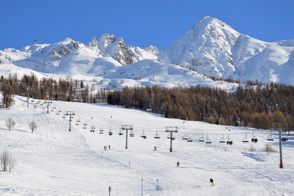Chairlifts running up gentle ski slopes below snowy mountains