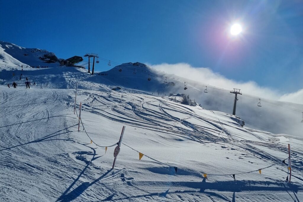 Chairlift above a groomed piste at Sansicario in the Vialattea ski area on a sunny day