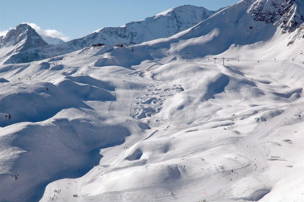 Open ski slopes and lift lines below rocky snow-covered peaks
